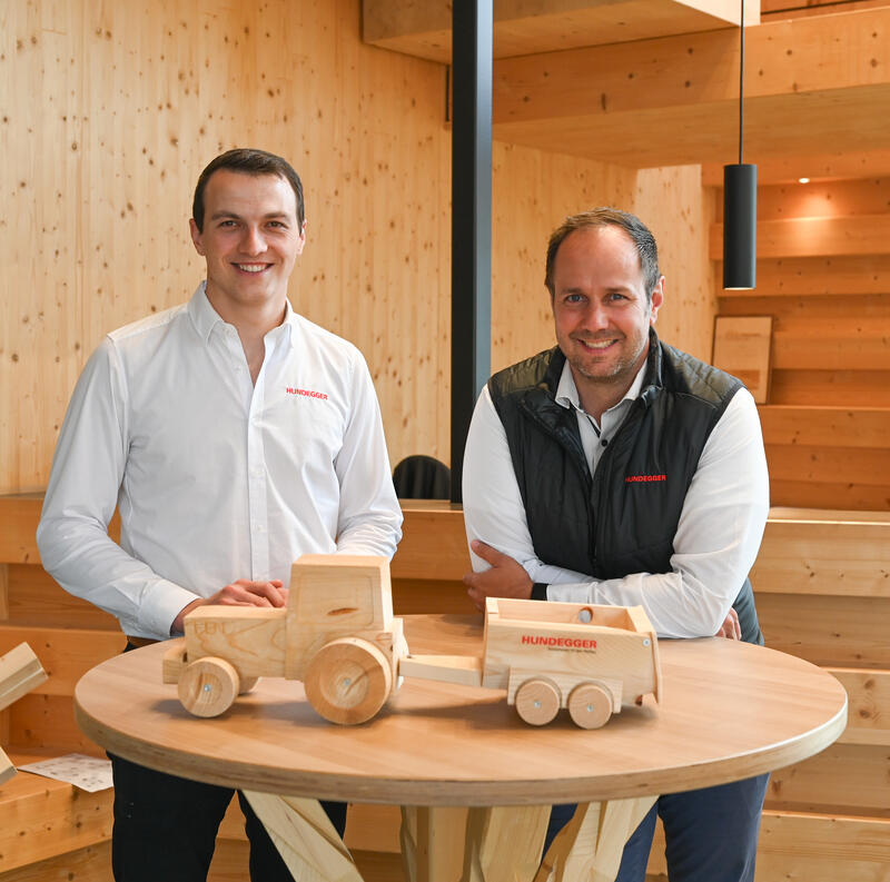 Josef Hundegger, Vorstandsvorsitzender, und Vorstand Rainer Auerbacher (v.l.) vor einem Holztisch